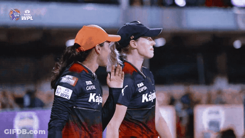 Two Female Cricket Players Standing Next To Each Other With The Wpl Logo On The Bottom GIF