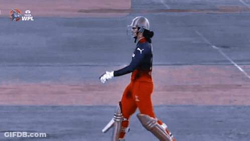 Two Female Cricket Players Standing Next To Each Other With Their Bats In Front Of A Tata Advertisement GIF