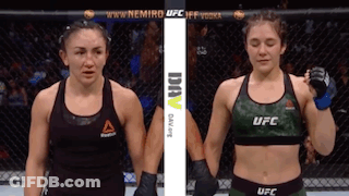 Two Female Fighters Are Standing Next To Each Other In A Cage . GIF