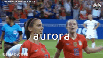 Two Female Soccer Players Are Standing On A Field And The Word Aurora Is On The Screen . GIF