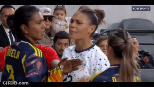 Two Female Soccer Players Talking With Baby In Background GIF