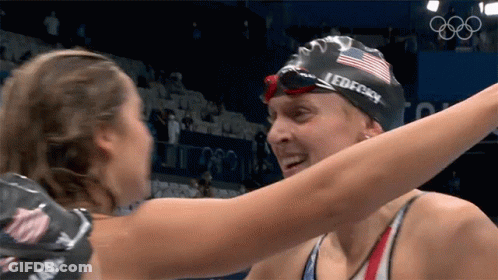 Two Female Swimmers Hugging One With Speedo Cap GIF