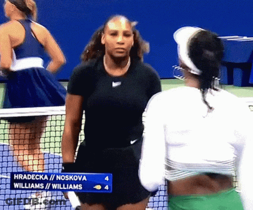 Two Female Tennis Players Are Standing Next To Each Other On A Tennis Court GIF