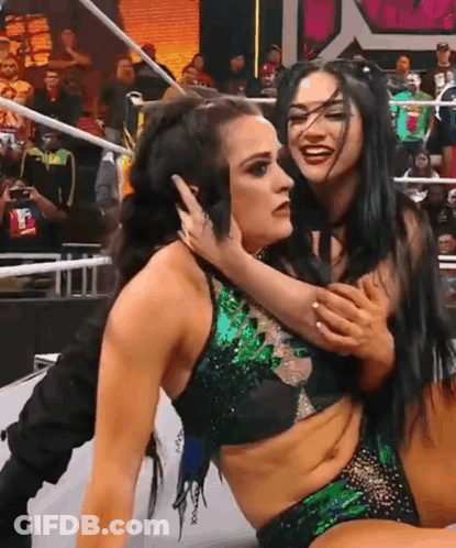 Two Female Wrestlers Are Hugging Each Other In A Wrestling Ring In Front Of A Crowd . GIF