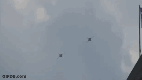 Two Fighter Jets Flying Near Building GIF