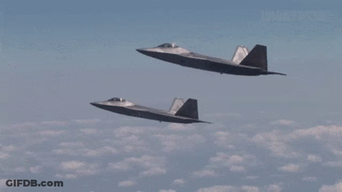 Two Fighter Jets Are Flying Side By Side In A Cloudy Sky GIF