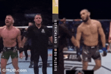 Two Fighters Are Standing In Front Of A Sign That Says Ostrichland Du Plessis GIF