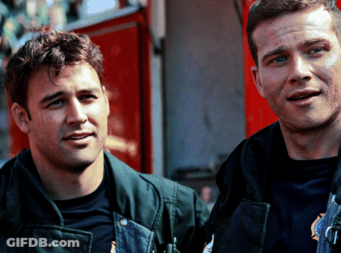 Two Firefighters Are Standing Next To Each Other And One Has A Badge On His Chest That Says ' Rescue ' On It GIF