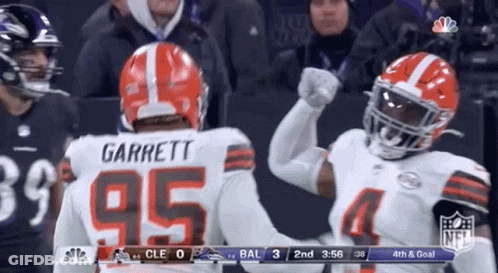Two Football Players Are Giving Each Other A High Five During A Football Game . GIF