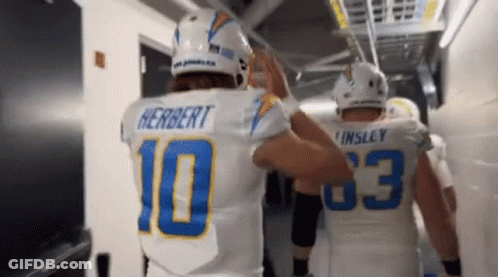 Two Football Players Are Giving Each Other A High Five In A Tunnel . GIF