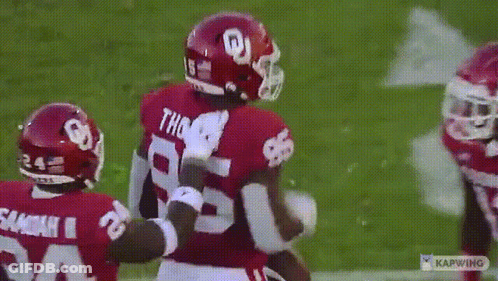 Two Football Players Are Hugging Each Other On A Field And One Of Them Has The Number 28 On His Jersey GIF