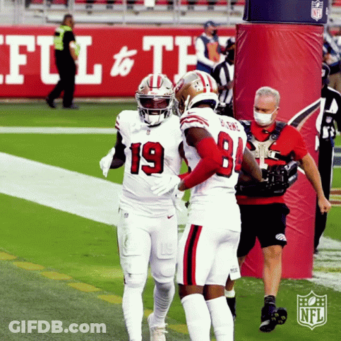 Two Football Players Are Hugging Each Other On A Field With The Nfl Logo In The Background GIF