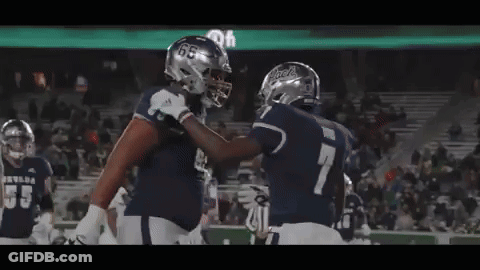 Two Football Players Are Hugging Each Other On The Field GIF