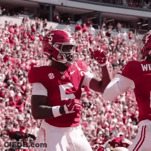 Two Football Players High Fiving In Front Of Crowd GIF
