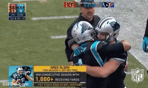 Two Football Players Hugging Each Other On The Field With The NFL Logo In The Corner GIF