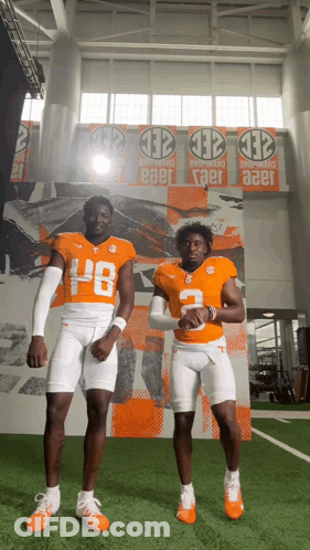 Two Football Players In Front Of Wall Banner Saying Taer GIF