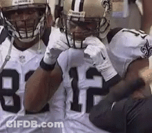Two Football Players In Helmets And Gloves Standing On Field GIF