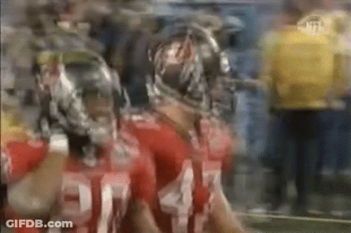 Two Football Players In Helmets Standing Side By Side GIF