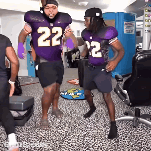 Two Football Players In Purple Uniforms With The Number 22 On Them GIF