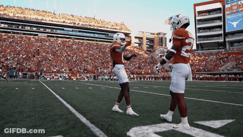 Two Football Players On A Field With A Scoreboard Behind Them That Says Texas Tech GIF