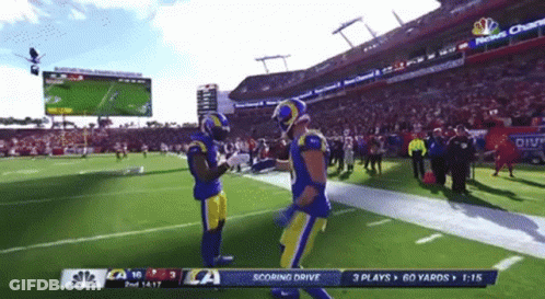 Two Football Players On A Field With A Scoreboard That Says Scoring Drive On It GIF