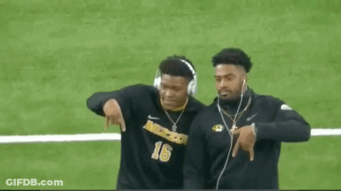 Two Football Players Wearing Headphones Are Walking On The Field . GIF