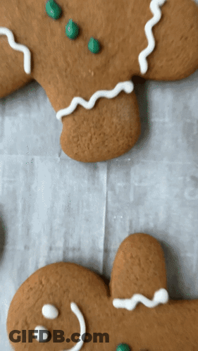 Two Gingerbread Men With Green Sprinkles On Them GIF