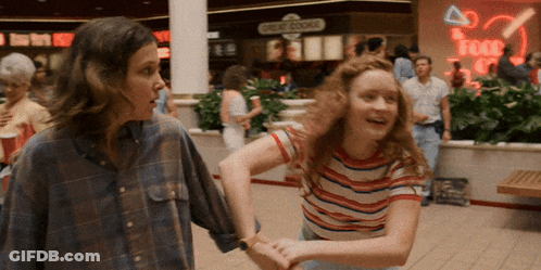 Two Girls Are Dancing In A Mall In Front Of A Sign That Says Credit Course GIF