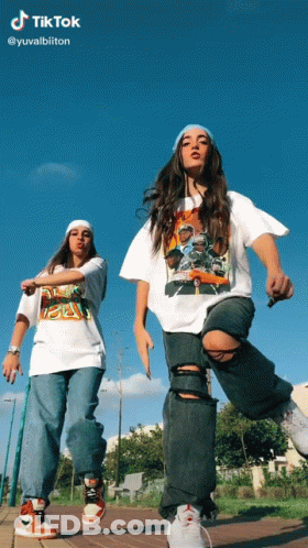 Two Girls Are Dancing In Front Of A Blue Sky With Tiktok Written At The Top GIF