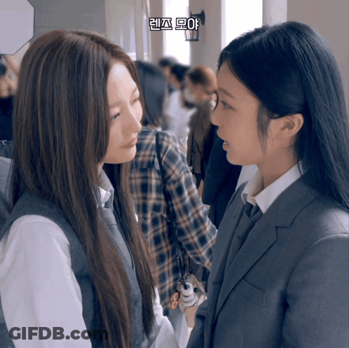 Two Girls Are Looking At Each Other In A Hallway With Korean Writing On The Bottom Right Corner GIF
