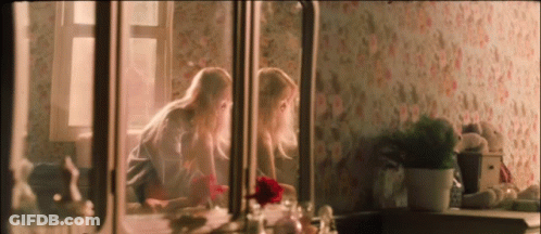 Two Girls Are Looking At Themselves In The Mirror GIF