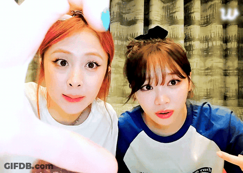 Two Girls Are Making A Heart Shape With Their Hands And One Of Them Is Wearing A Shirt That Says ' Rock ' GIF