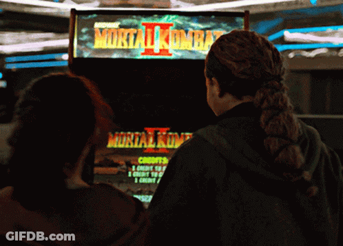 Two Girls Are Playing A Video Game Called Mortal Kombat 2 GIF