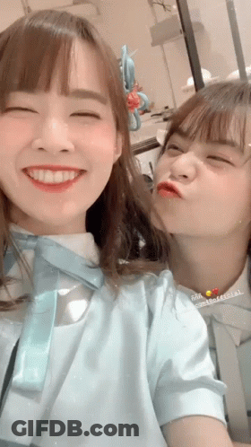 Two Girls Are Posing For A Picture And One Is Kissing The Other 'S Cheek GIF