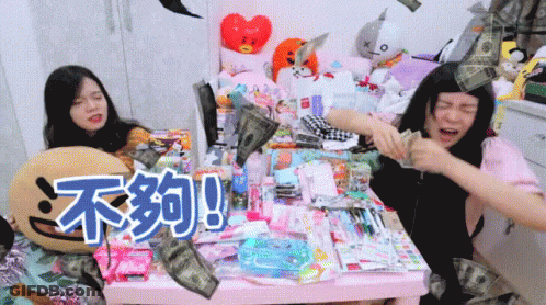 Two Girls Are Sitting At A Table With Chinese Writing On The Table GIF