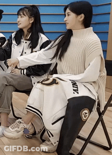 Two Girls Are Sitting In Chairs With One Wearing A Jacket That Says Twice GIF