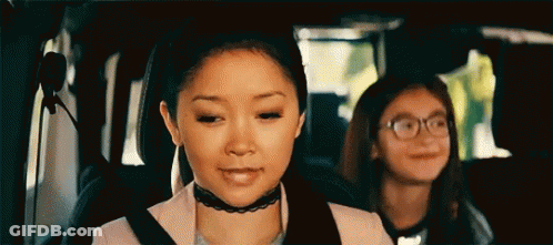 Two Girls Are Sitting In The Back Seat Of A Car . One Girl Is Wearing Glasses And A Choker . GIF