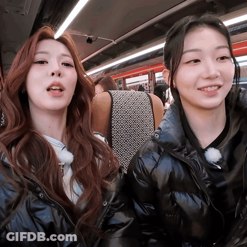 Two Girls Are Sitting Next To Each Other On A Bus And Smiling For The Camera GIF