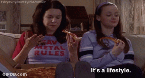 Two Girls Are Sitting On A Couch Eating Pizza And One Has A Shirt That Says " Raw Metal Rules " GIF