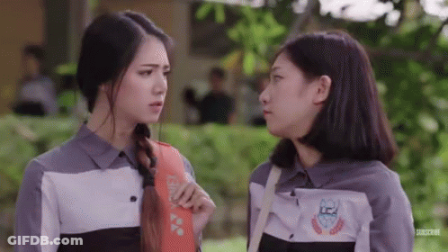 Two Girls Are Standing Next To Each Other And Talking To Each Other In A Park . GIF