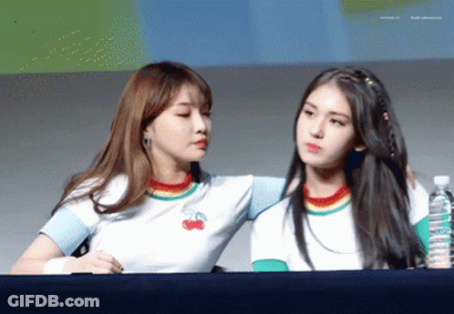 Two Girls Are Standing Next To Each Other With One Wearing A Rainbow Shirt With Cherries On It GIF