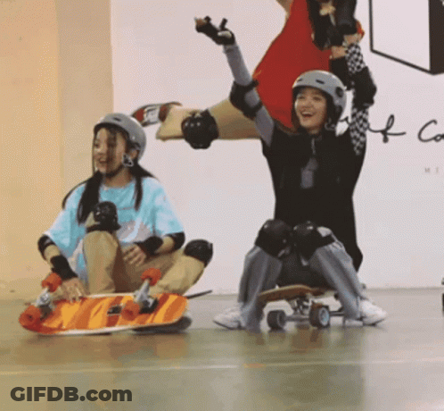 Two Girls In Helmets And Knee Pads On Skateboards GIF