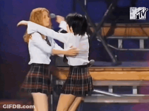 Two Girls In Plaid Skirts Hugging On Stage GIF