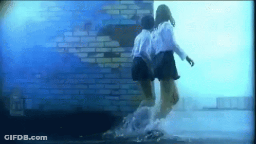 Two Girls Jumping In Water In Front Of Brick Wall GIF