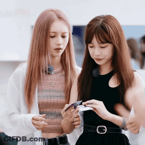 Two Girls Looking At Phone With Letter G On Belt GIF