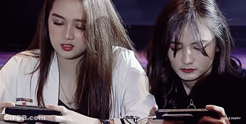 Two Girls Playing Game On Phones With Noble Puppy GIF