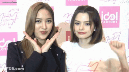 Two Girls Posing In Front Of Idol Factory Sign GIF