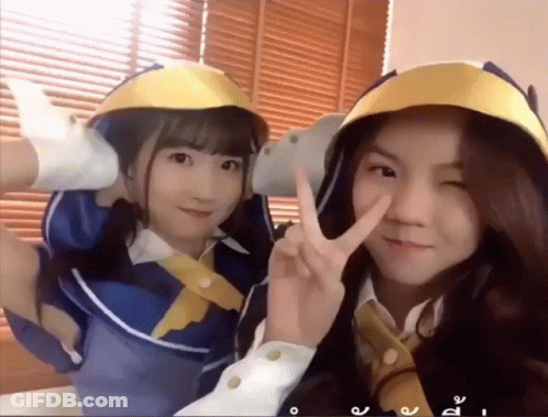 Two Girls Posing, One In Yellow Helmet GIF