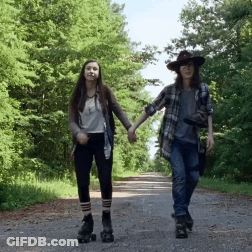 Two Girls Rollerblading On A Road Holding Hands GIF