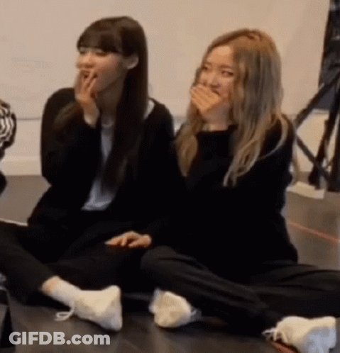 Two Girls Sitting On Floor Laughing Covering Mouths GIF